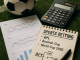 Flat lay photo of sports betting materials including a soccer ball, calculator, performance charts,